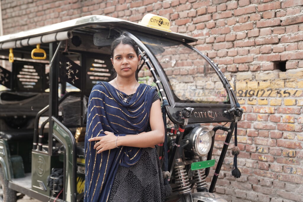 Woman standing proudly by her electric rickshaw