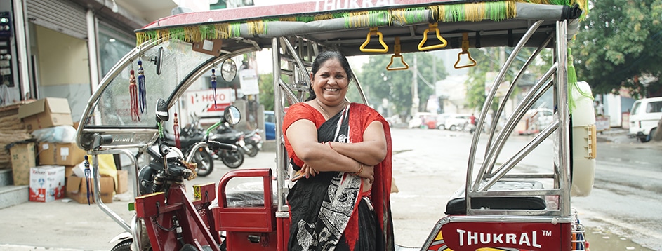 Woman Transporter in India standing by her electric rickshaw